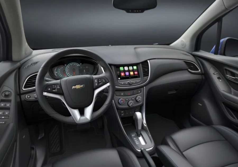 A cabine lembra o Onix, mas muda no toque e no conforto. Materiais mais macios e bancos mais densos tentam resolver críticas antigas em viagens longas.